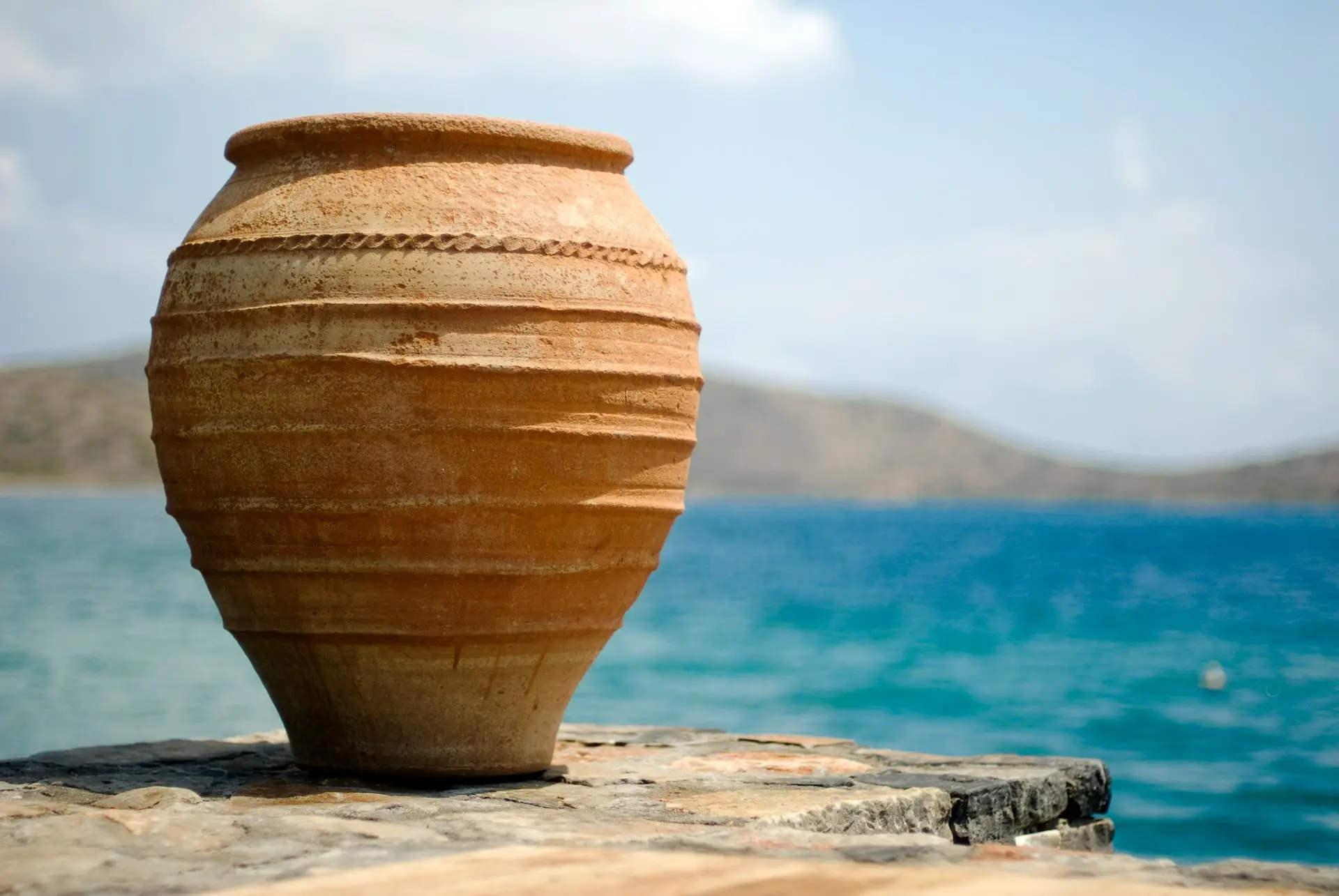 brown clay pot on white sand near body of water during daytime